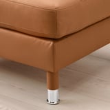 Close-up of a brown leather footstool on a wooden floor, showcasing its sturdy chrome legs and high-quality upholstery.