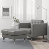 Modern living room with grey LANDSKRONA lounge chair & ottoman, black and white decor, large window, minimalist lamp.
