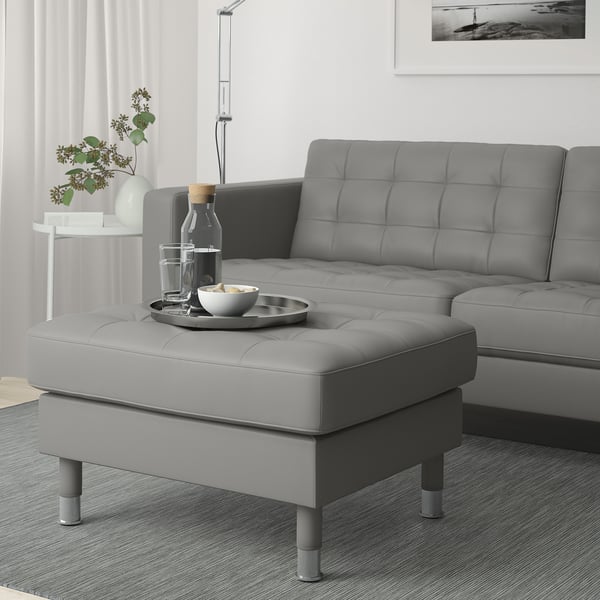Modern living room with a grey LANDSKRONA seat & ottoman. Leather & fabric, square cushions. Ottoman holds tray, bowls, & glasses. Matches sofas size.