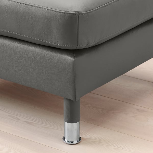 Close-up of a modern, gray leather ottoman with chrome-plated legs on a wooden floor.