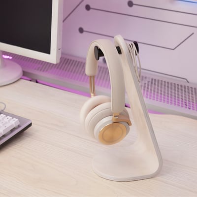 White headset stand with headphones on desk near keyboard.