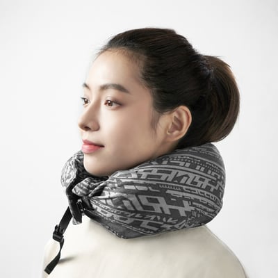 Woman with updo and light top using adjustable travel neck pillow.