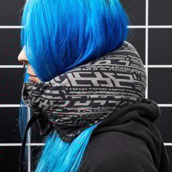 A person wears a LÅNESPELARE blue neck pillow with black text design over a black hoodie.