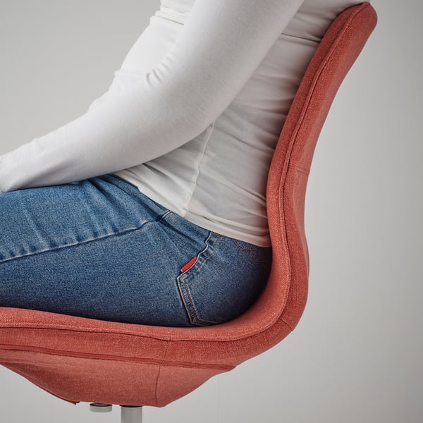 A person sitting in an orange office chair, leaning back. The chair supports good posture with lumbar support and tilt function.