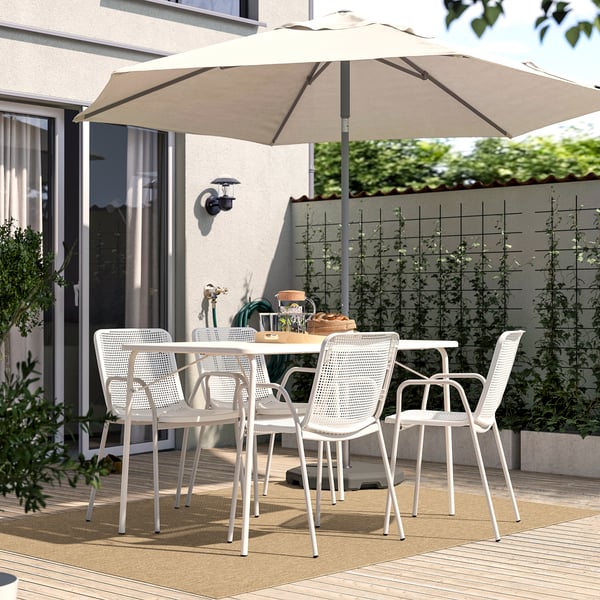 Beige LÄTTBETONG rug on patio with chairs & umbrella, cozy outdoor dining.