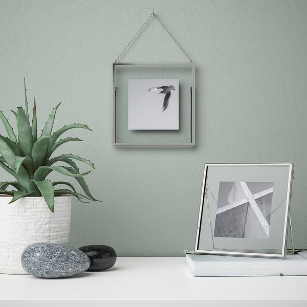 Modern frame on wall and table with plant and picture.