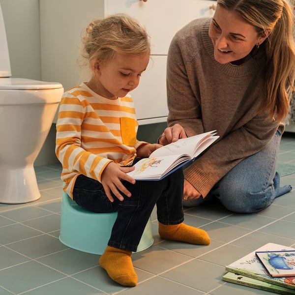 Woman and girl reading on green toilet.