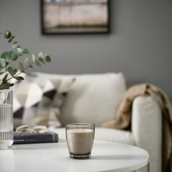 LINDLÖNNSKOG candle beside vase, book, glasses on table near couch with throw.