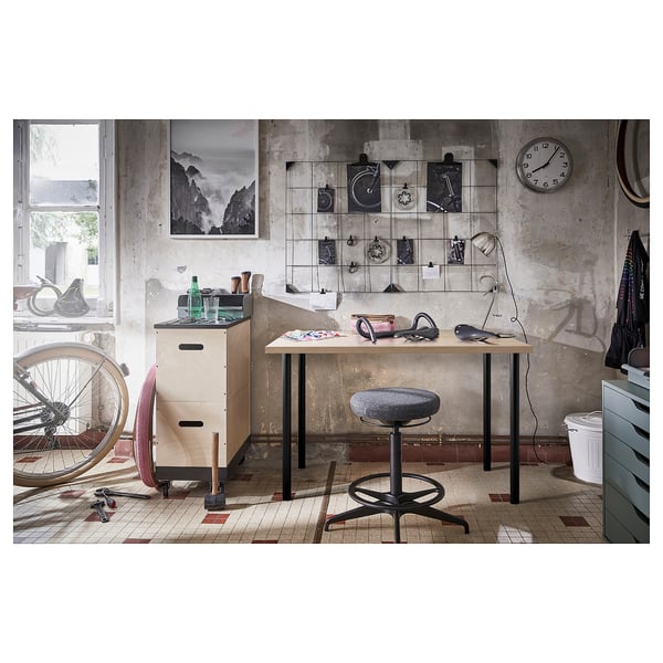 Industrial-style workspace with linmon table, chair, and decor, featuring a clock, art, and storage.