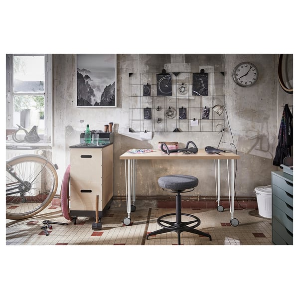 Modern office chair, desk, bike parts, and wall clock tools.