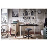 Industrial-style workspace with adjustable desk and stool, metal bike.