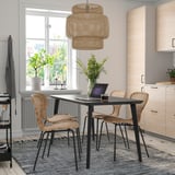 Cozy LISABO dining setup with black table, natural chairs, pendant light, and plants.