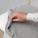 A hand adjusts a removable chair cover, highlighting its easy-clean feature.