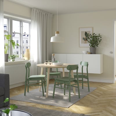 Modern dining area with LISABO table and green chairs, wood floor, large window, and hanging lamp.