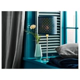 Beautiful blue bedroom decor. Modern lamp, turquoise vase with white flower, and folded blue blanket.