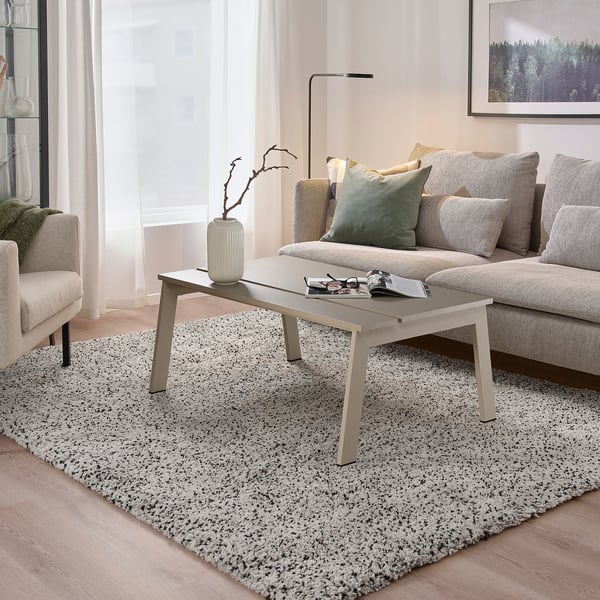 Modern living room with LJUNGSBRO multi-use table, light wood floor, grey rug, and large couch with pillows.