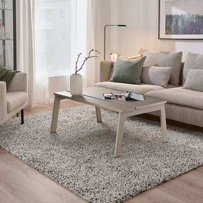 Modern living room with LJUNGSBRO multi-use table, light wood floor, grey rug, and large couch with pillows.
