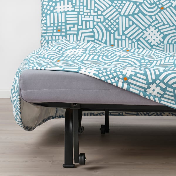 Patterned chair-bed with gray base and wheels, partially converted into a bed.