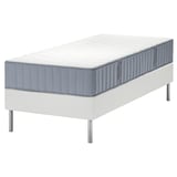 White modern bed setup with gray quilted mattress on stainless steel legs.