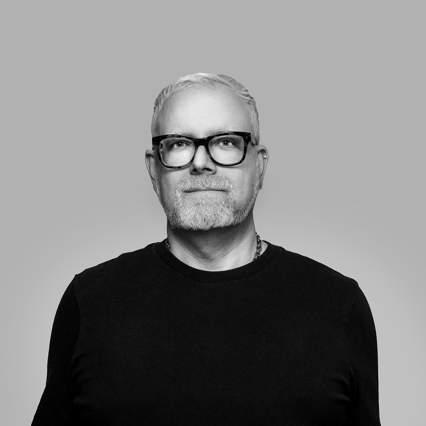 Black and white portrait of the designer with glasses, wearing a dark shirt.