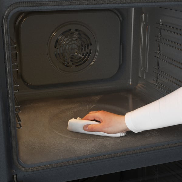 Cleaning oven interior with cloth. Shows self-cleaning feature.