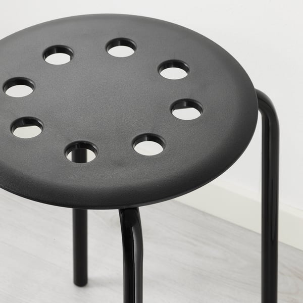 Black modern stool with circular seat and multiple holes, supported by sleek metal legs.
