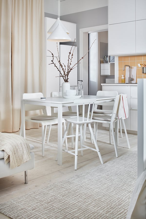 MELLTORP dining set with moisture-resistant table and stackable chairs. Pendant light and vase with branches create a cozy minimalist space.