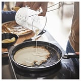Pouring pancake batter into MIDDAGSMAT pan. Character count: 48