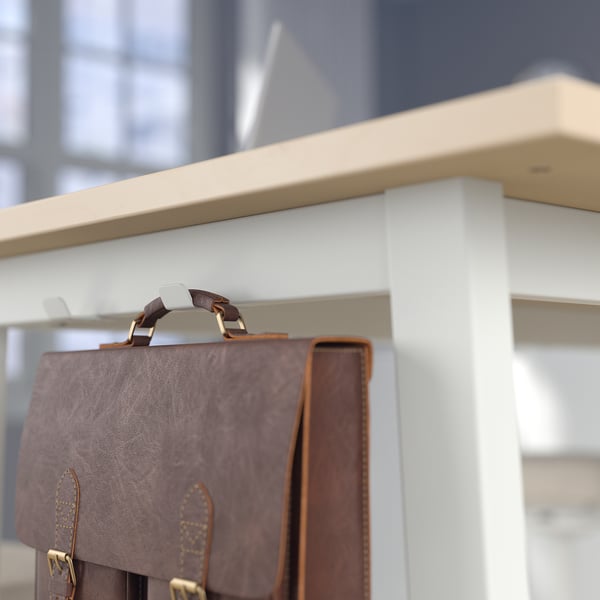 Brown leather bag hangs on a white shelf with hooks, ideal for keeping belongings secure during work sessions.