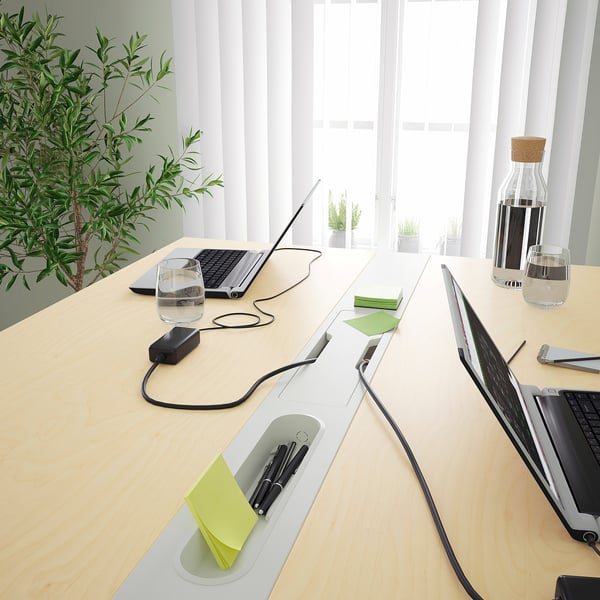 A sleek, modern conference table with integrated cable management, a footrest, and a section for pens, ideal for meetings.