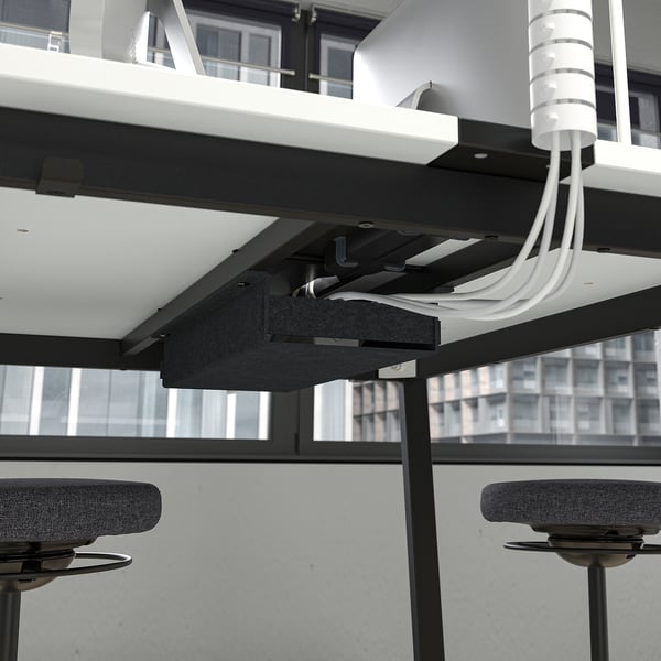 Modern office setup with suspended, adjustable table and chairs, connected by visible cables, suitable for conferences.
