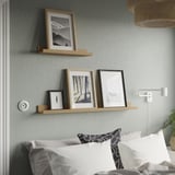Two ledges with photos; bed, pillows, lamp.