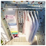 Closet with MULIG storage, floral wallpaper, linens, light wood floor, white door.