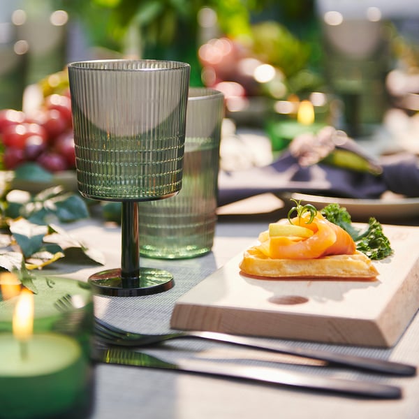 Wooden NÄBBFISK cutting board with smoked salmon, glasses, and candle.