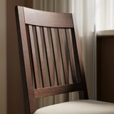 Close-up of modern, sturdy wooden chair with vertical slats on backrest, highlighting high-quality craftsmanship and natural wood texture.