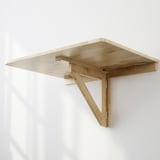 Foldable wall-mounted desk in light wood. Folds flat when not in use, saving space. Attaches securely to walls with proper hardware.