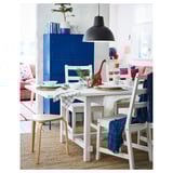 Bright dining area with white table, chairs, blue cabinet, red dinosaur, black lamp.
