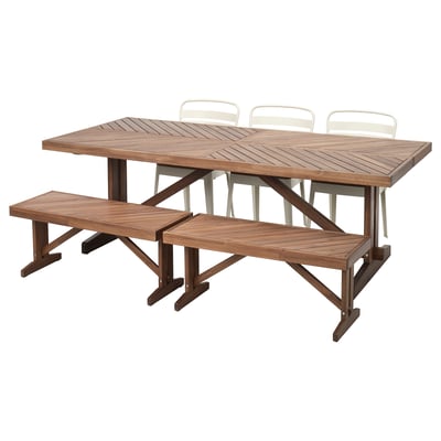 A brown wooden outdoor table with two matching benches and four white chairs.