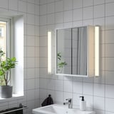 Bathroom with large NYSJÖN mirrored cabinet above sink, reflecting room and plant.