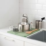 Kitchen countertop featuring NYSKÖLJD mat, holding utensils and a blender for protection.