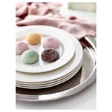 Stack of white porcelain plates, featuring five colorful rounded candies on top plate, displayed on metallic tray, perfect for serving treats.