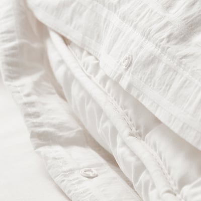 Close-up of crinkled white bedding with textured dobby-weave, showing hassle-free plastic press-stud closure at bottom for easy use.