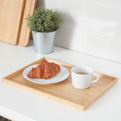 A rectangular OSTBIT bamboo tray with a white plate and mug. Small, fits well on kitchen counters.