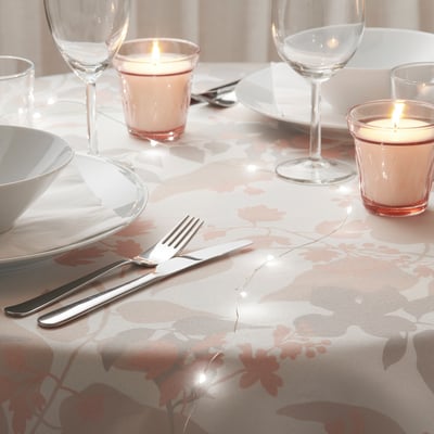 Floral tablecloth, candles, wine glasses, cutlery - cozy setting.
