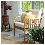 Bright room with wicker chair, yellow cushions, potted plants, and wood-burning stove.