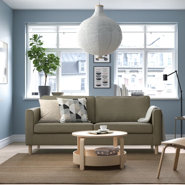 Modern living room with PÄRUP olive sofa, natural wood coffee table, and a large window. Cozy & minimalist decor.