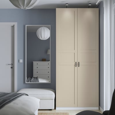 Modern bedroom with tall beige PAX wardrobe, sleek design, large mirror, more storage than dresser and bed.