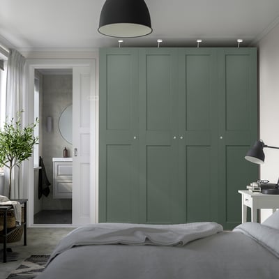 Modern bedroom with tall green PAX wardrobe and sleek compartments.