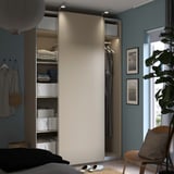 Modern bedroom with open PAX wardrobe in beige. Folded clothes, boxes, hangers, and sliding door.