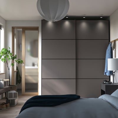 Modern bedroom with dark gray wardrobe, white bed, wooden floor, hanging lamp.
